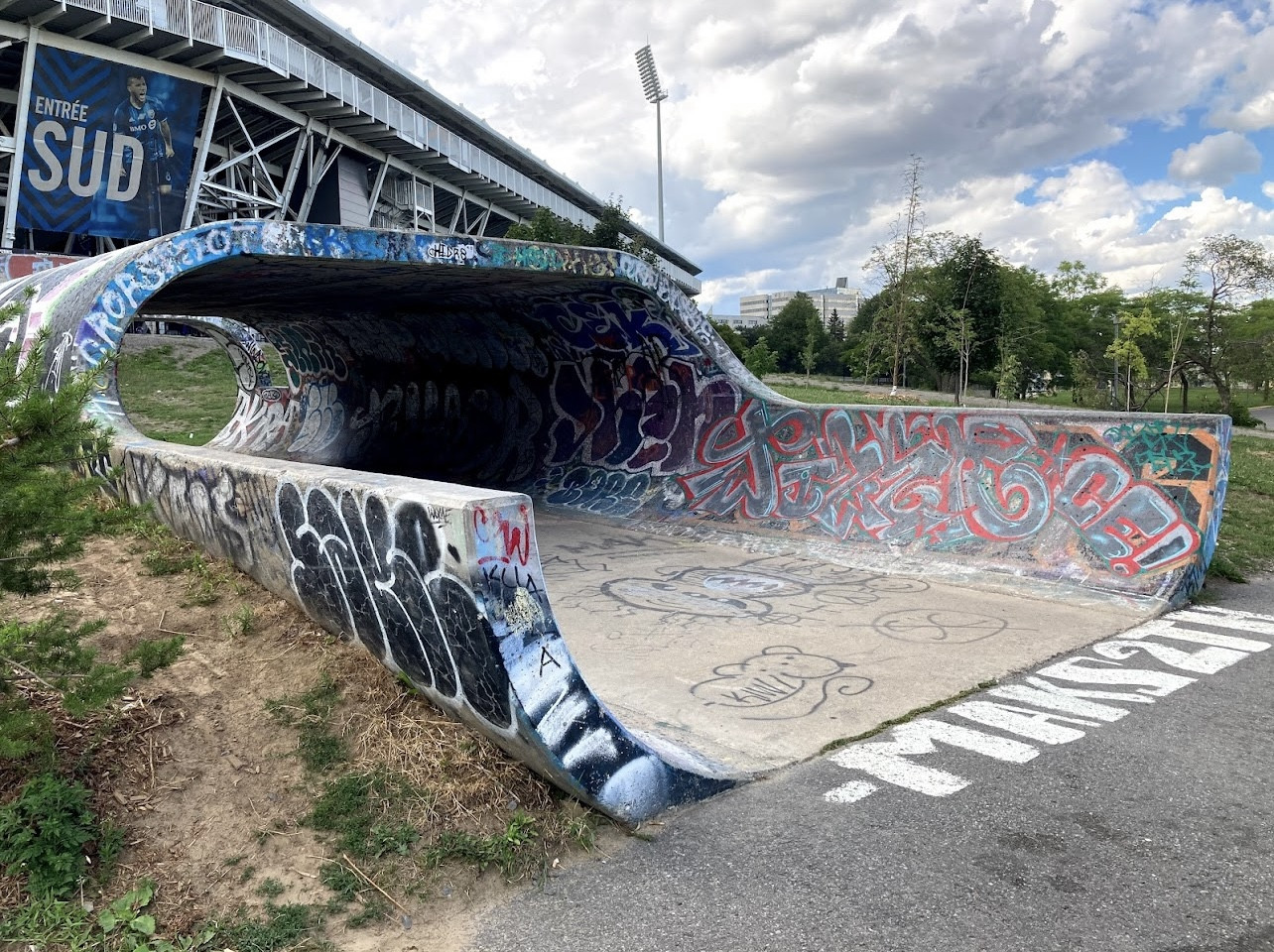 The Big O skate spot in Montreal, featuring a famous graffiti-covered concrete pipe wave structure outdoors near the Olympic Stadium.