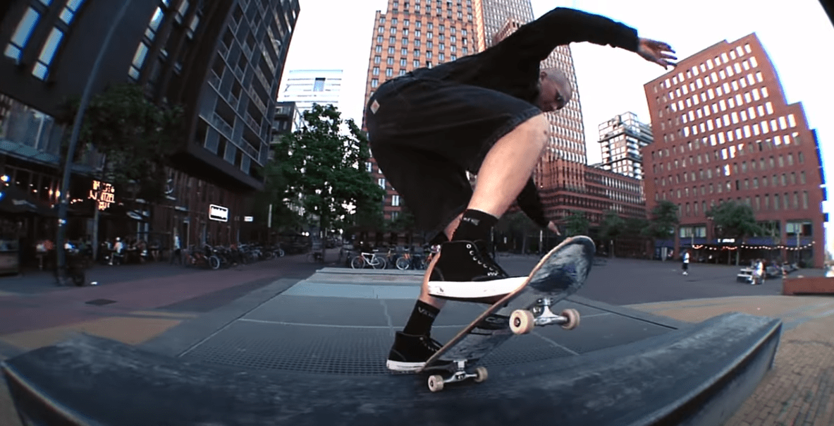 A low-angle fisheye photograph of a skateboarder Aleksi "Aatsi" Suovaara performing a frontside bluntslide trick on a ledge in a plaza.