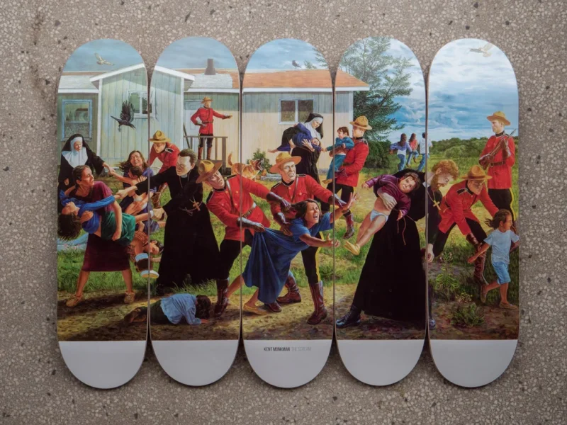 Five skateboard decks laid out on a textured surface, displaying Kent Monkman’s The Scream—a continuous painting of Mounties, nuns, and other figures in a rural scene.